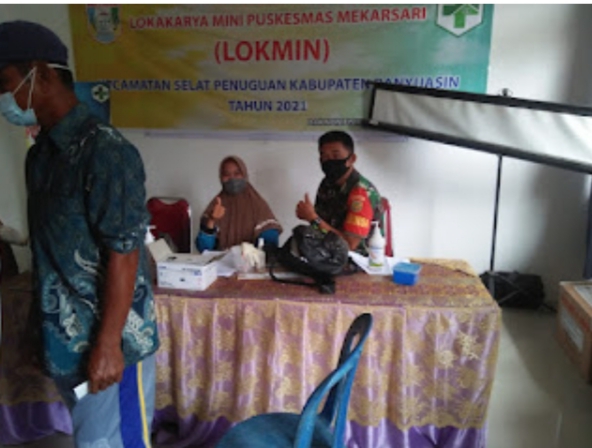Sertu Ujang Fikri melaksanakan pendampingan Vaksinasi di Puskesmas Mekarsari Kecamatan Selat Penuguan